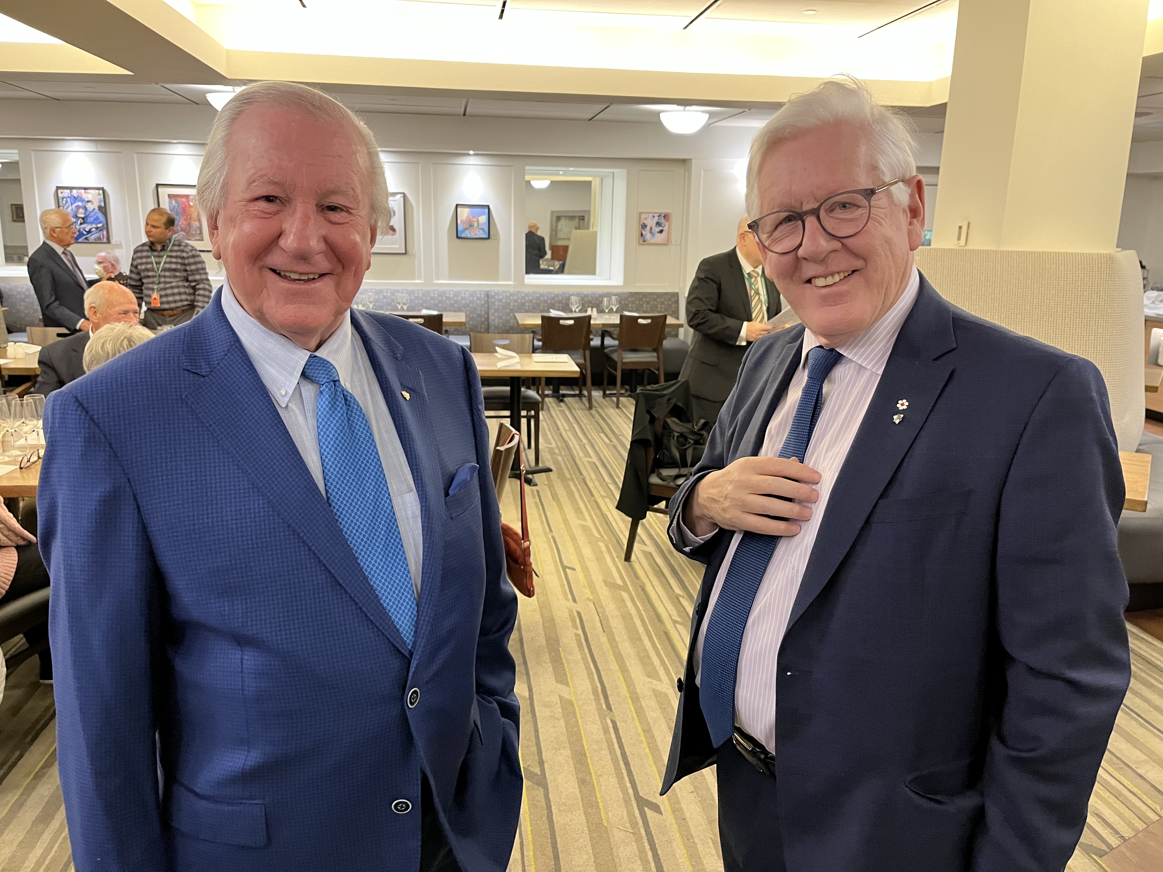 two men in suits smile at the camera