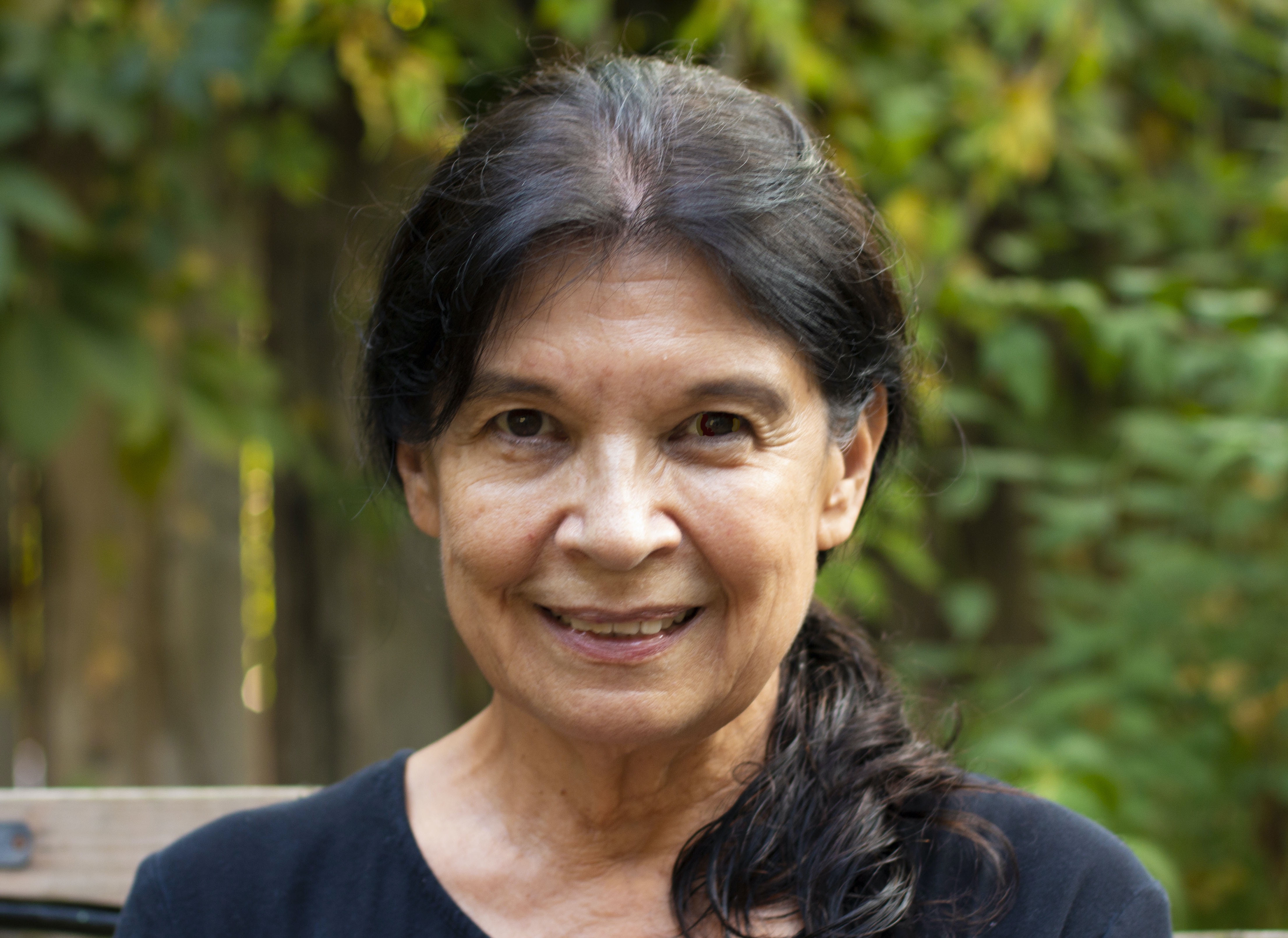 Close up of a smiling woman with her brown hair pulled back in a pony tail