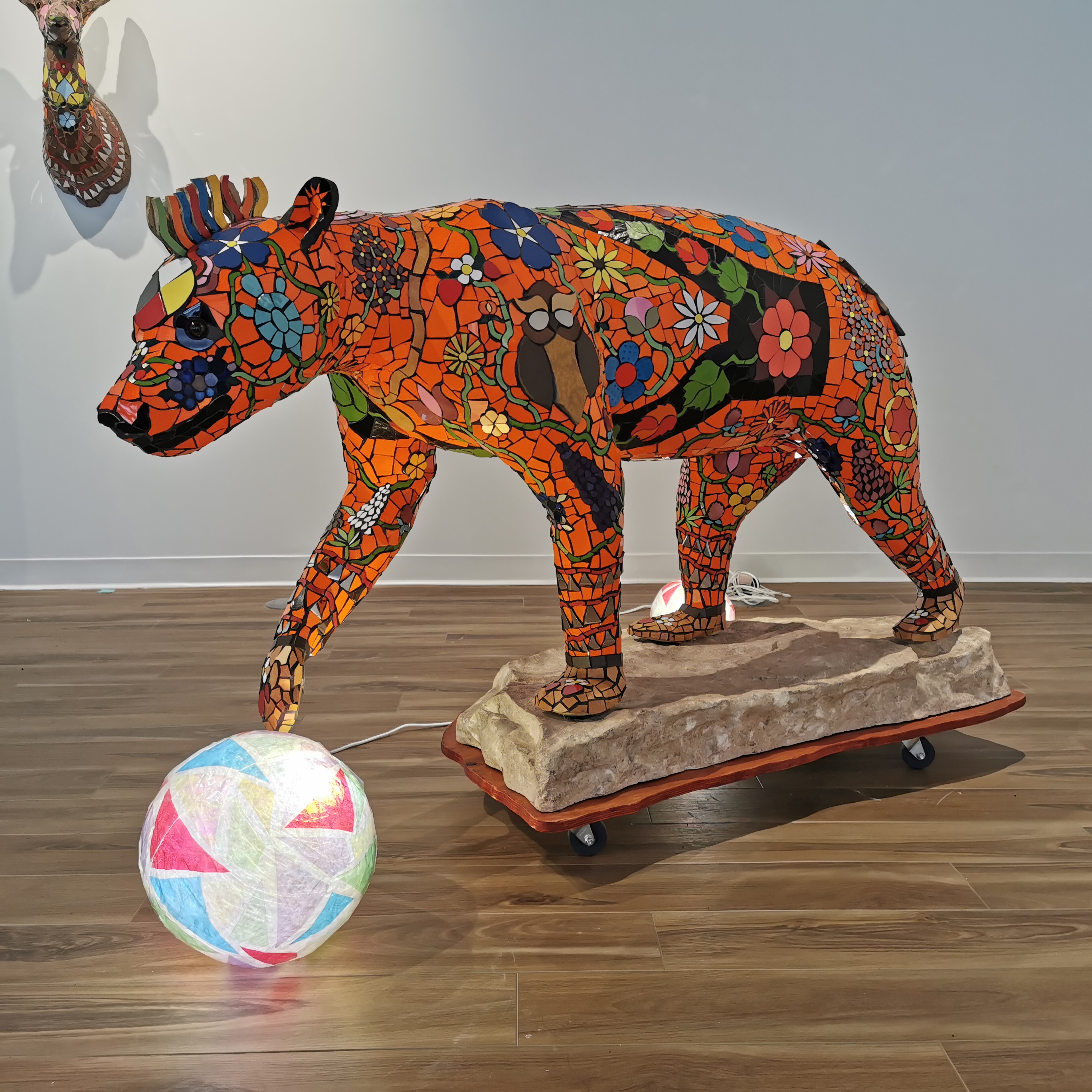A bear form covered in colourful mosaic tile pieces in an art gallery