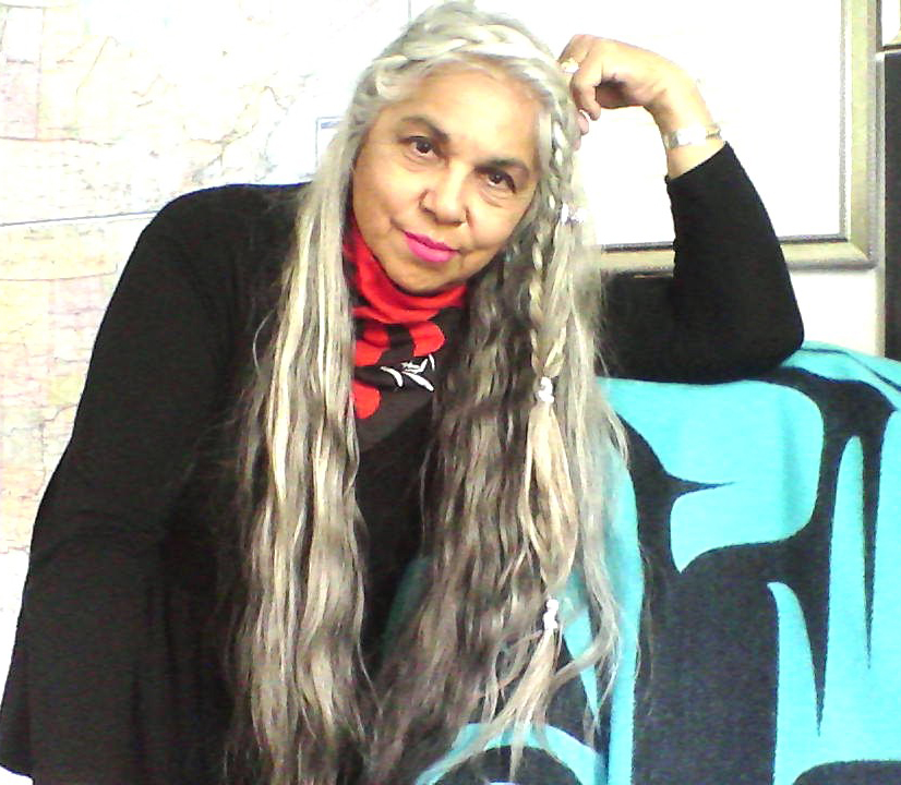 A woman with long silver hair leans on her bent arm