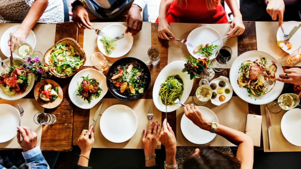 Amigos a partilhar uma refeição numa mesa cheia de comida.
