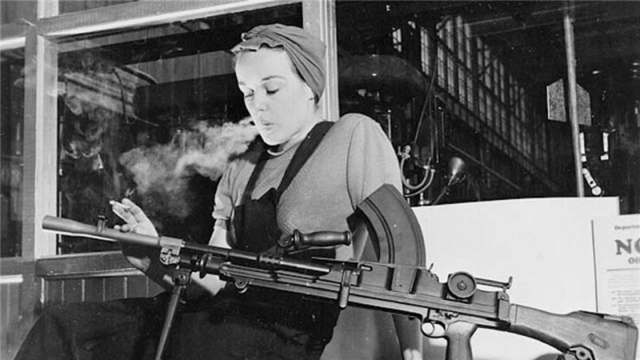 woman in head scarf smokes while holding gun