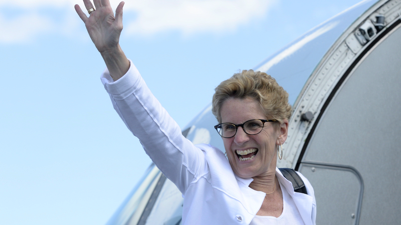 woman in white jacket smiles and waves