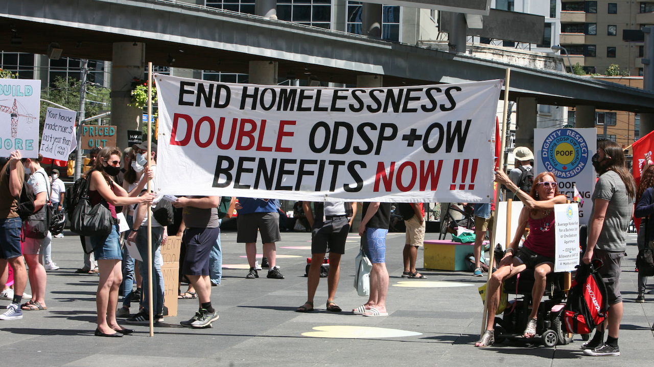 protesters holding banner reading "end homelessness: double ODSP and OW benefits NOW"